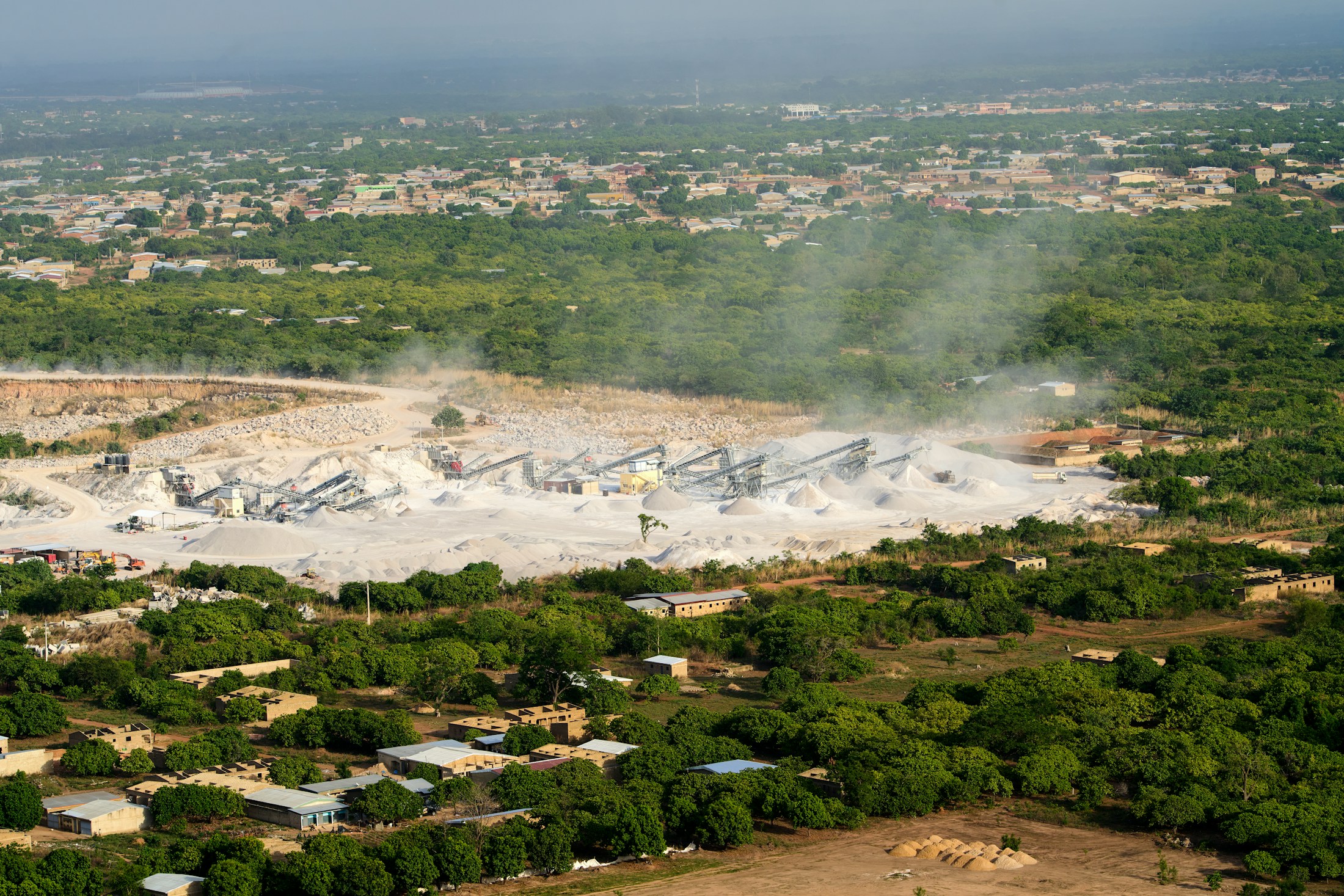 Aerial view of an open quarry with layered rock faces and material-handling equipment